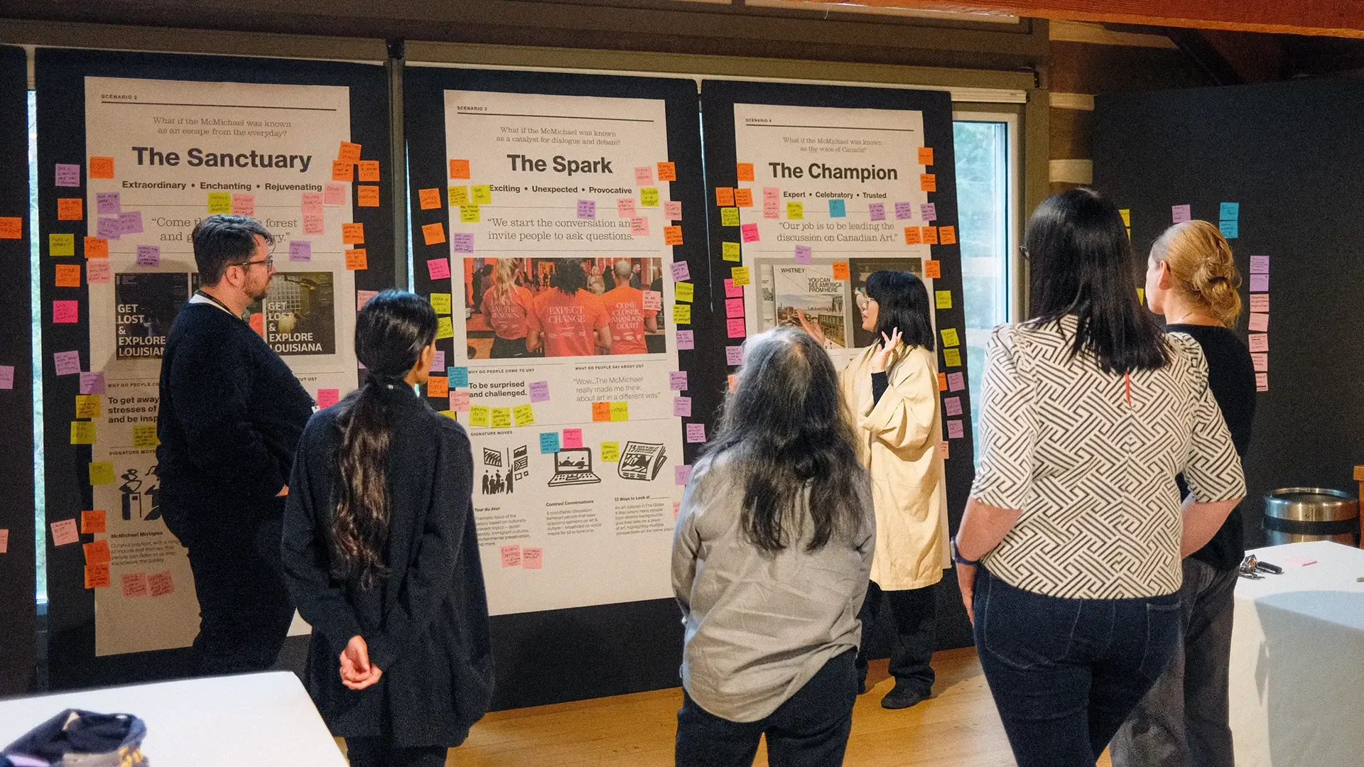People gathered around large boards with sticky notes and research material.