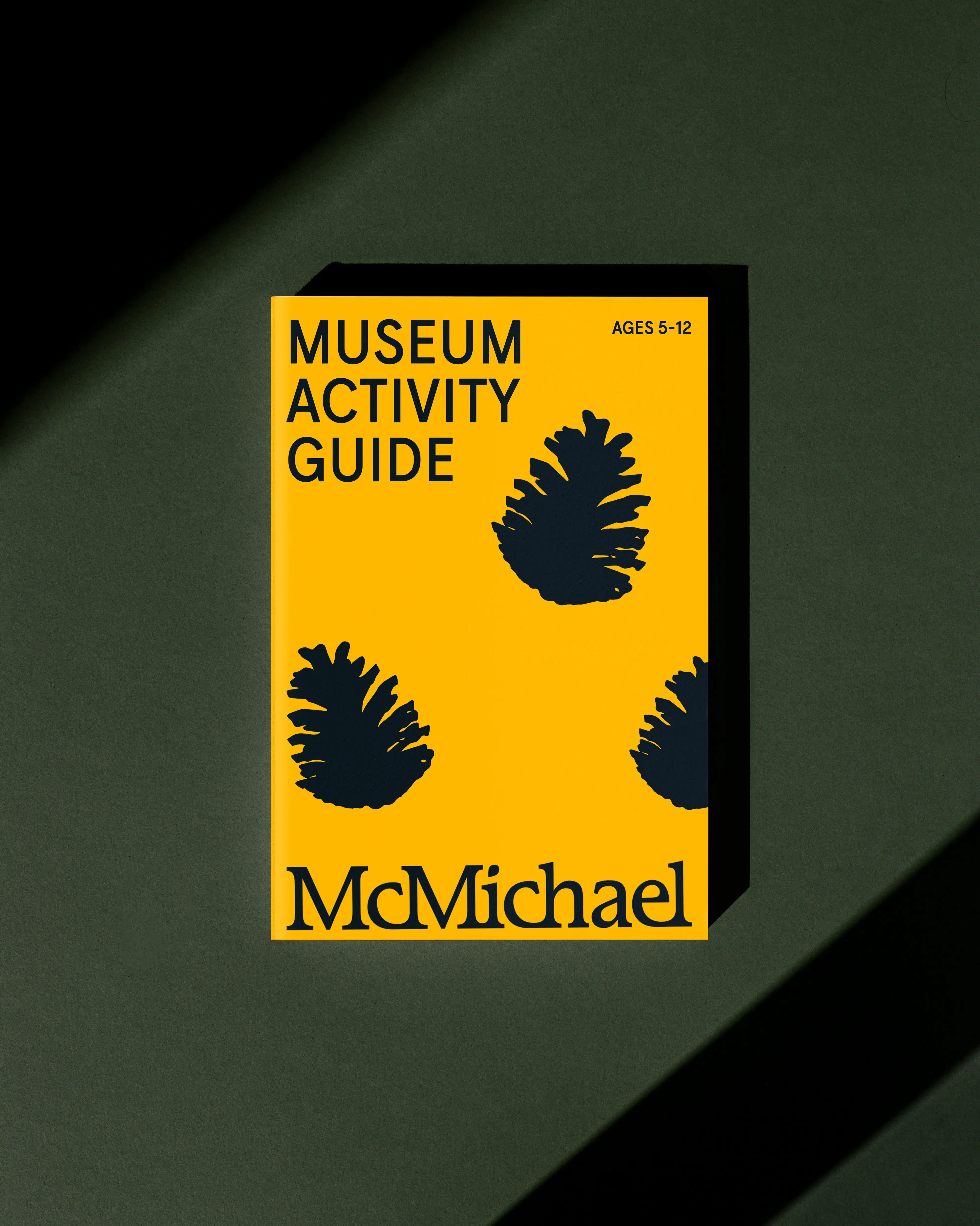 McMichael yellow branded activity guide with black pine cones