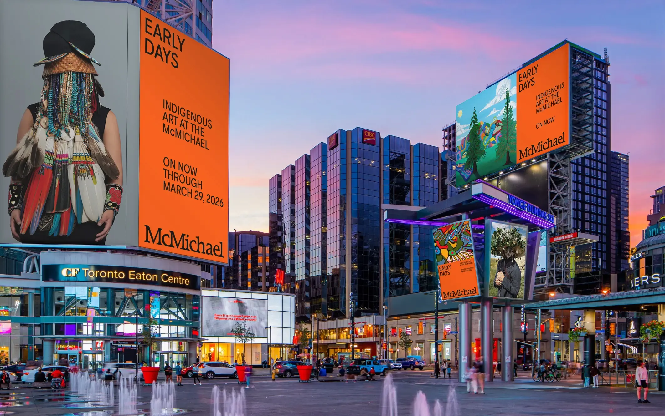 Sankofa Square with digital billboards advertising McMichael Early Days. The sky is at sunset.